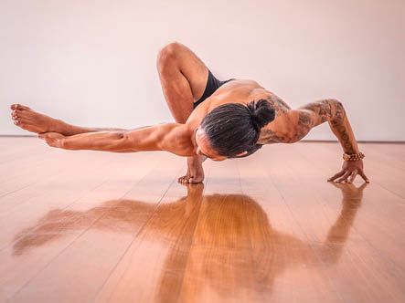 Male yoga instructor in an arm balance pose