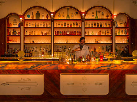 A bartender pours a drink in front of a well stocked top shelf bar