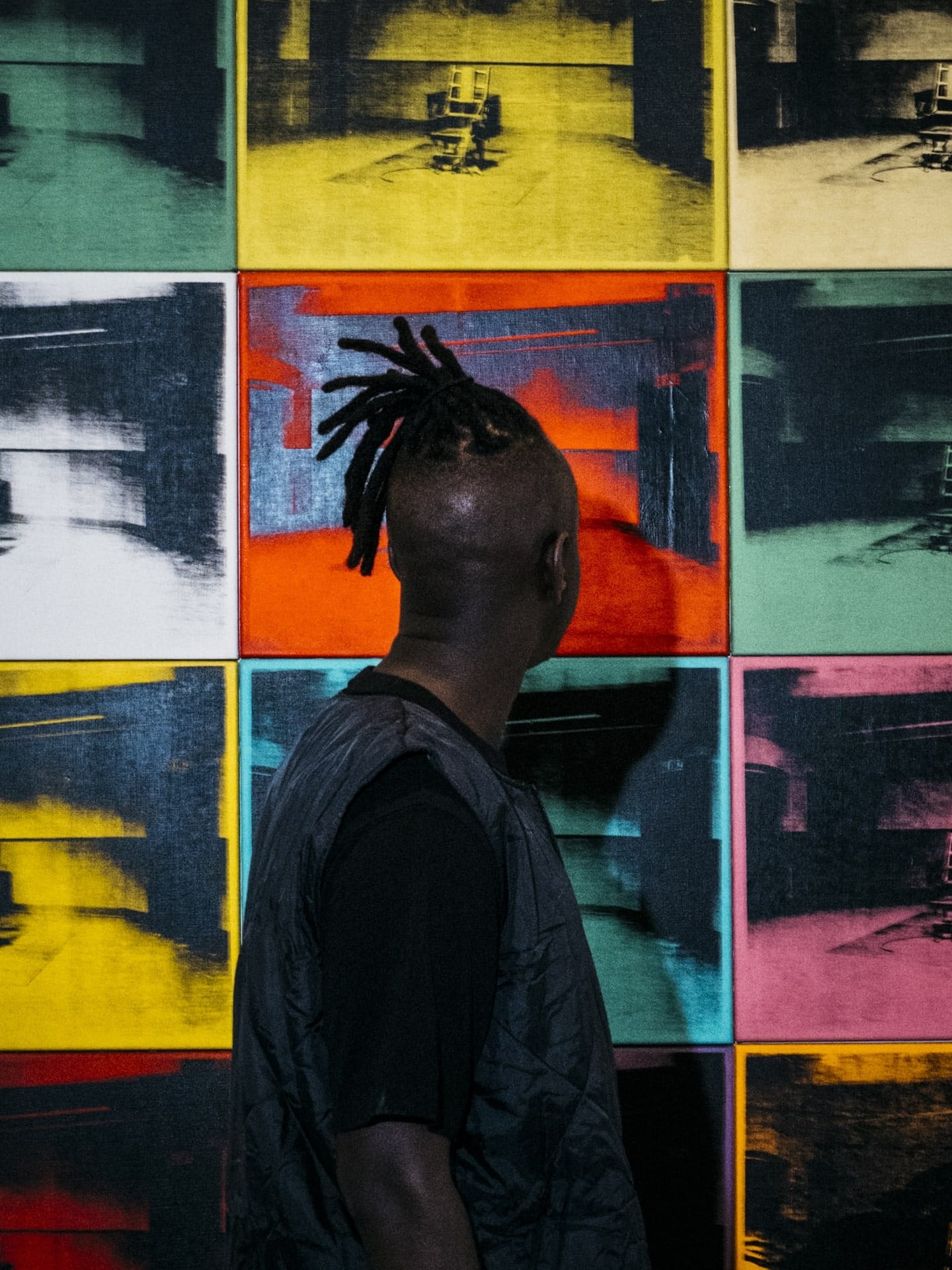 Man standing in front of multicolored wall of art